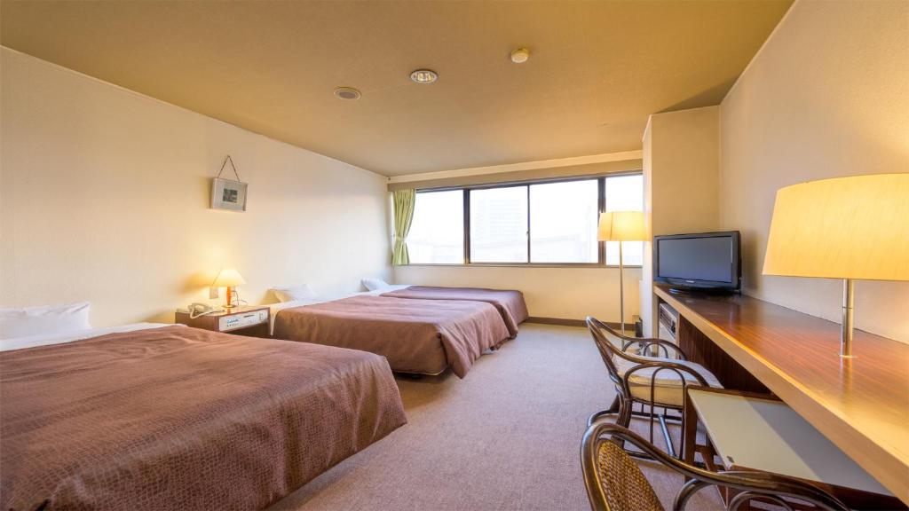 山形市Hotel Sakuranbo的酒店客房设有两张床和一张书桌及电视