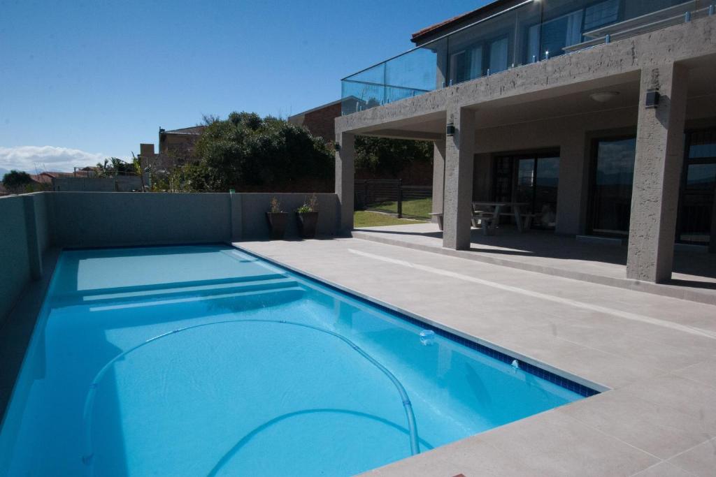 哈坦柏斯25 On Rooiels的一座大型蓝色游泳池,位于房子旁边