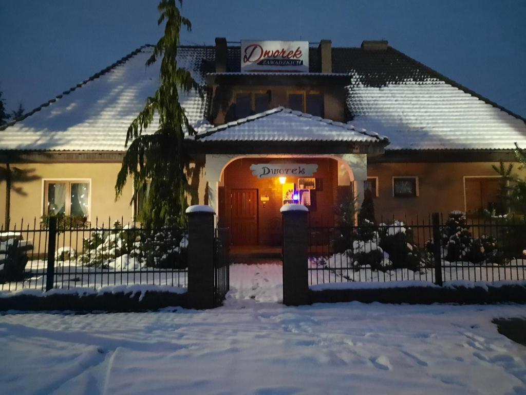 KruszynDworek Zawadzkich的雪中的房子,门上有一个标志