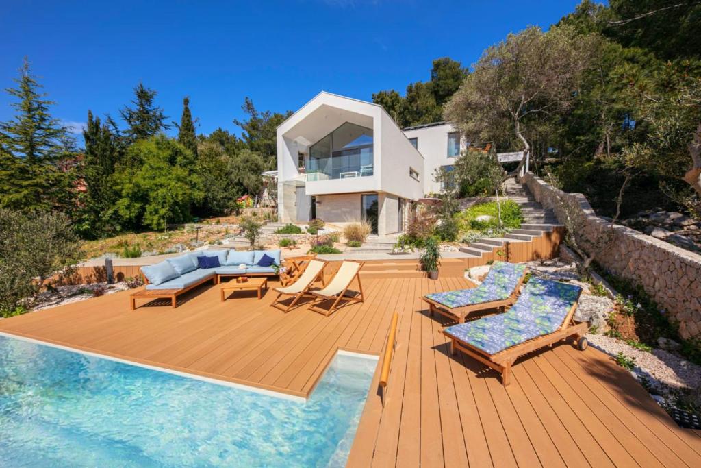 木洛希尼Villa del Mar Deluxe的房屋设有木甲板、椅子和游泳池