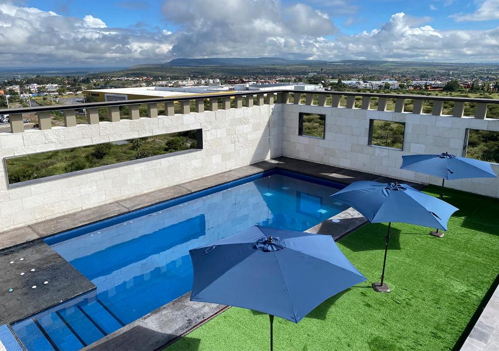 圣米格尔-德阿连德Hotel MX San Miguel de Allende的一座大楼顶部的游泳池,配有遮阳伞