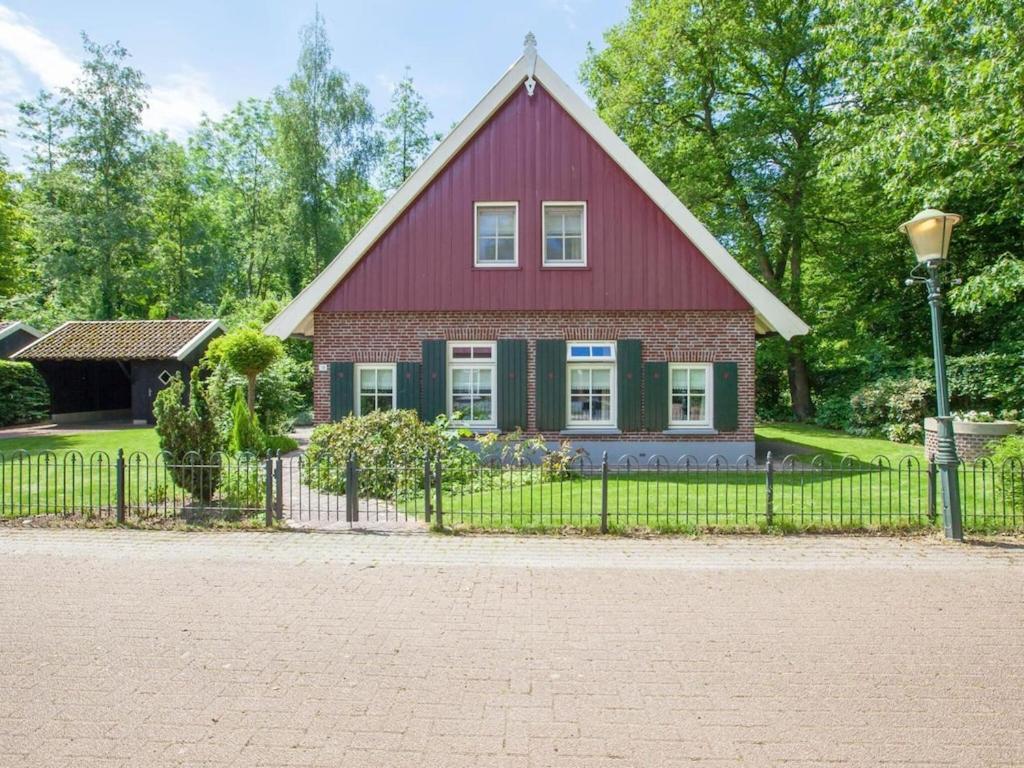 MeddooSnug holiday home in Winterswijk Meddo with a private garden的一座红色绿色的房子,设有围栏