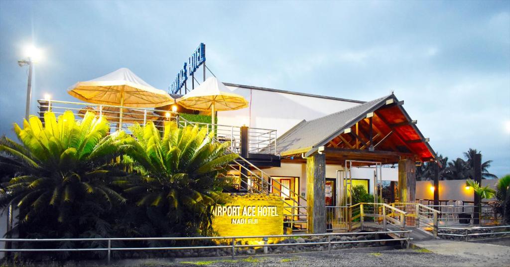 南迪Airport Ace Hotel的一间位于餐厅前面的遮阳伞和棕榈树