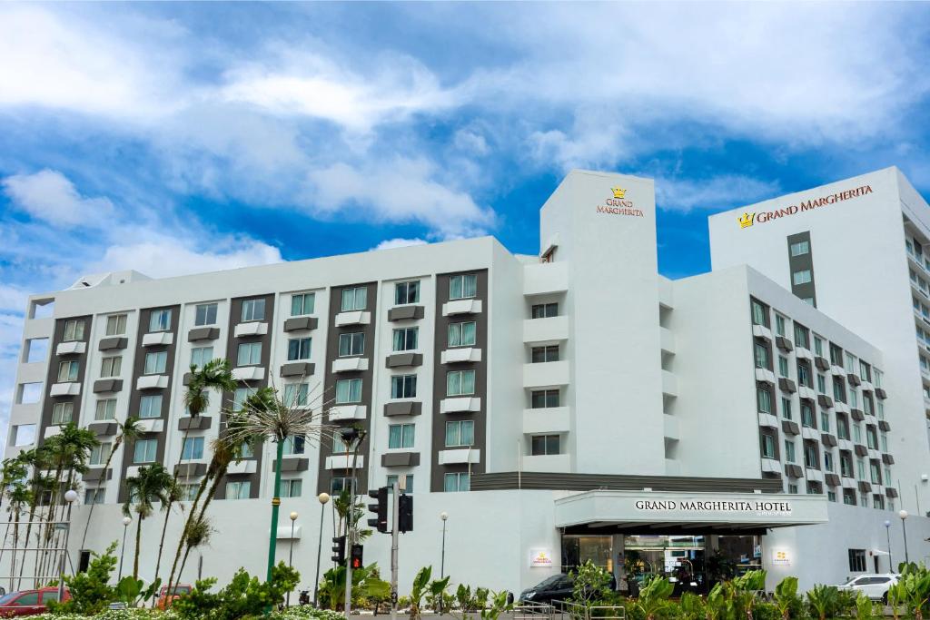 古晋玛格丽特大酒店的一座白色的大建筑,前面有棕榈树