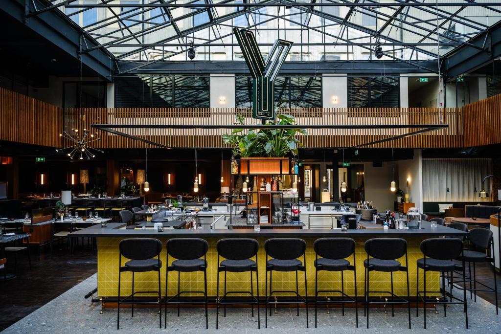 根特Yalo Urban Boutique Hotel Gent的餐厅设有配备黄色椅子的大型酒吧