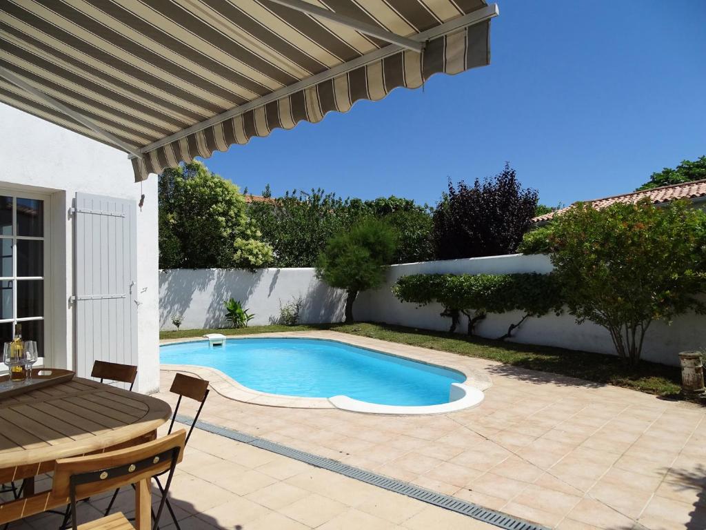 雷岛圣玛丽TETHYS VILLA AVEC PISCINE ET PROCHE DE LA MER的一个带桌子的游泳池和一个庭院