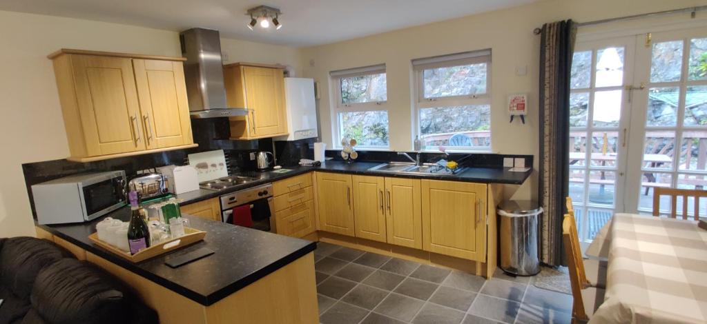 阿罗柴尔The Cobbler Cottage - Loch Lomond and Arrochar Alps的厨房配有木制橱柜和黑色台面