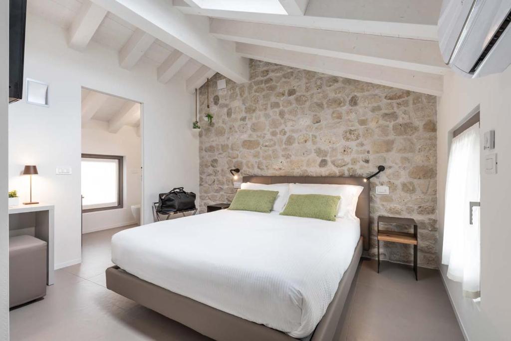 Roveredo in PianoPortone180 Guest House的卧室配有白色的床和石墙