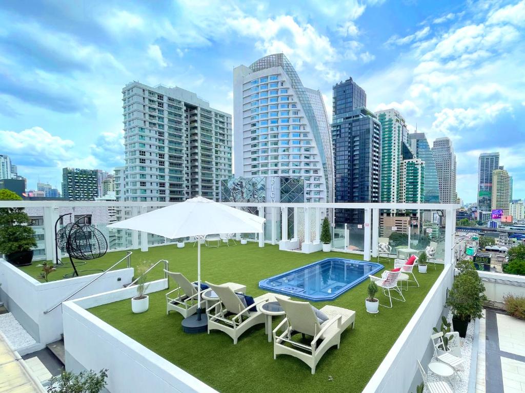 曼谷素坤逸富丽华阿索克酒店的一座带椅子的屋顶露台和一座位于大楼内的游泳池