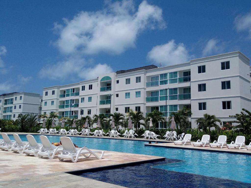 嘎林海斯港Palm Village Acqua - Apartamento Premium - Em frente à piscina - Porto de Galinhas的一座带椅子的游泳池和一座建筑的酒店