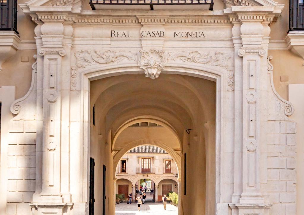 塞维利亚Casa de la Moneda Residences Sevilla的建筑中的拱门,上面有标志