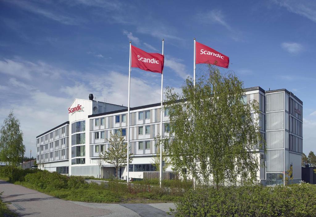 阿兰达Scandic Arlandastad的前面有两面红旗的建筑