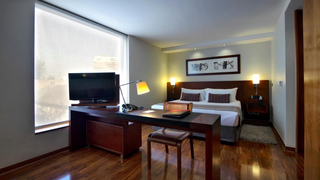 圣地亚哥Select by Time的一间卧室配有一张床和一张书桌及电视