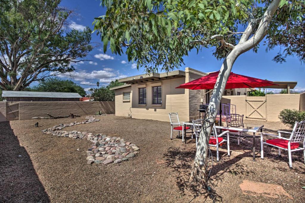 土桑Tranquil Tucson Home with Yard - Walk to U of A的庭院配有桌椅和红色遮阳伞。