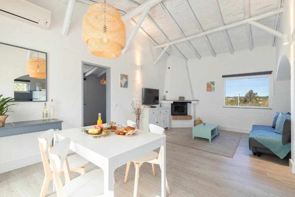 Mexilhoeira GrandePalmeiras Cottages的白色的用餐室以及带白色桌椅的客厅