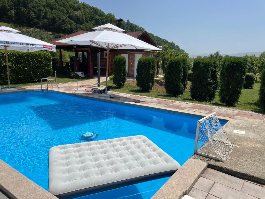 巴尼亚卢卡Family resort TRAPISTI的一个带白色椅子和遮阳伞的游泳池
