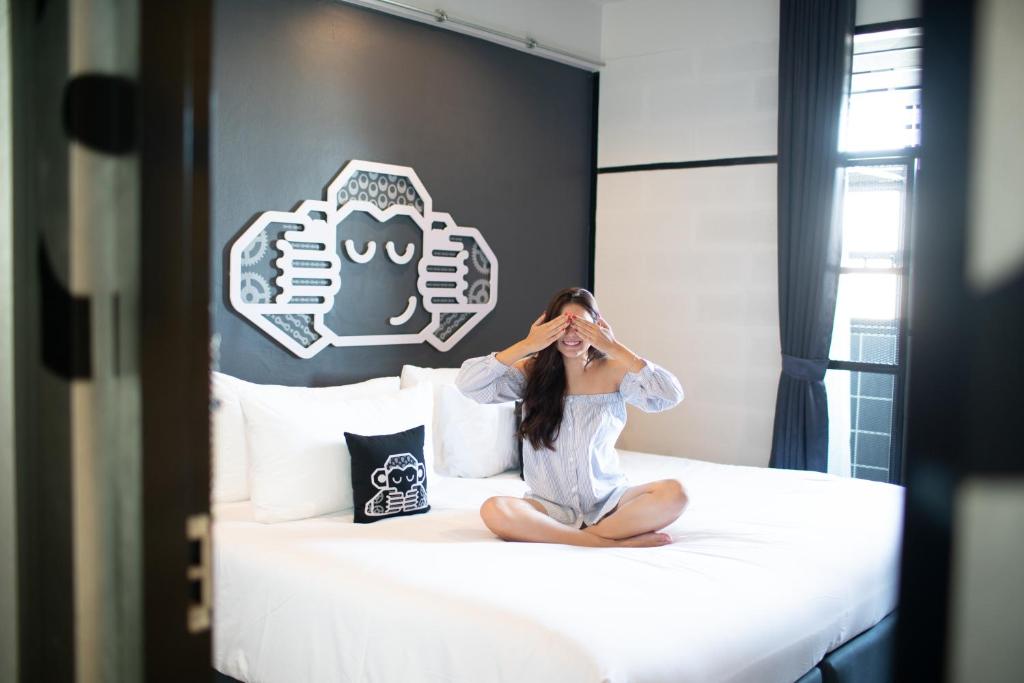 素叻Blu Monkey Hub & Hotel Surat Thani的坐在卧室床上的女人