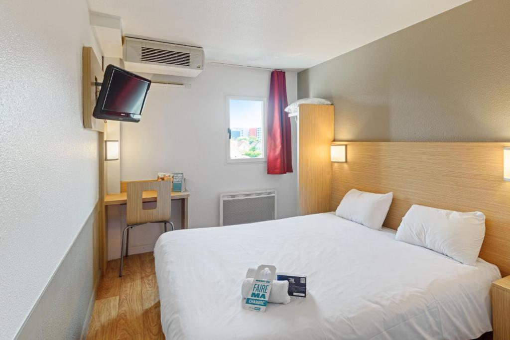 盖拉德Kyriad Direct Annemasse - Genève的一间酒店客房,配有一张白色的床和一张书桌