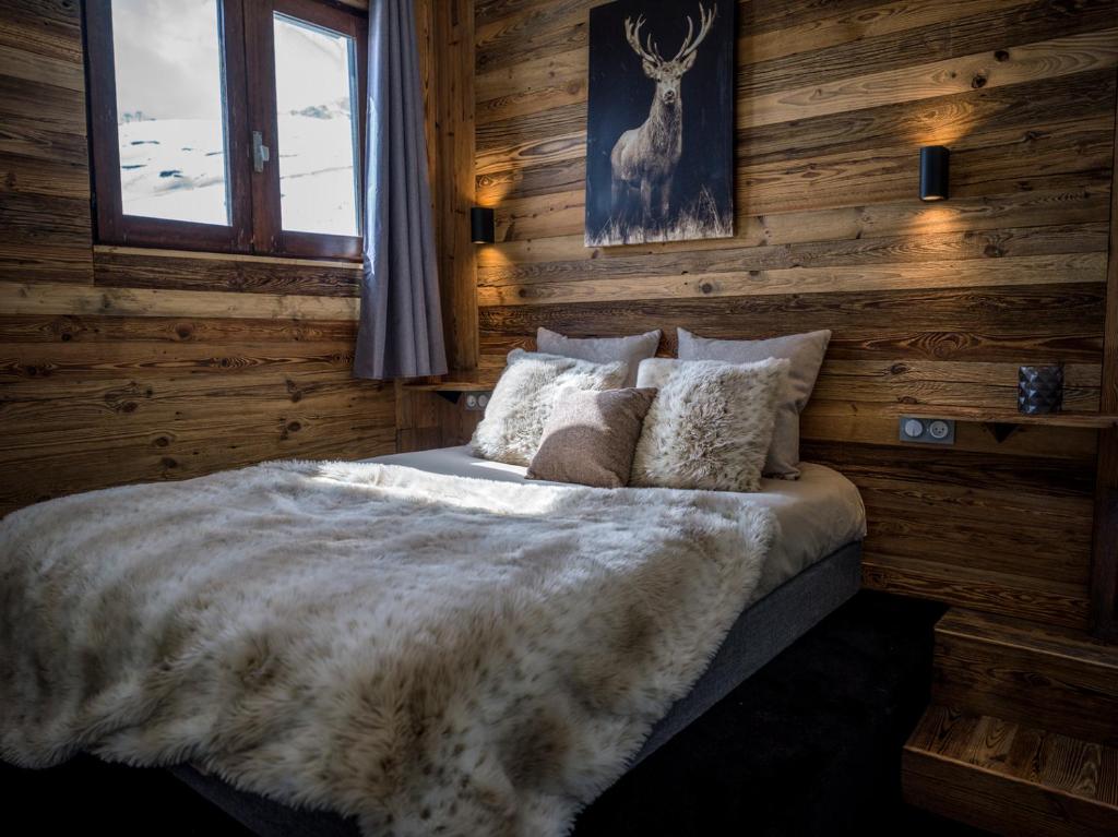 蒂涅Magnifique Duplex Oneigedor Départ ski aux pieds et vue montagne的一间卧室配有一张带木墙和窗户的床。