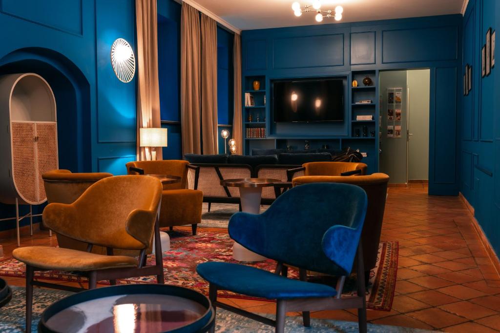 魏玛Hotel Erbenhof的客厅设有蓝色的墙壁、椅子和电视