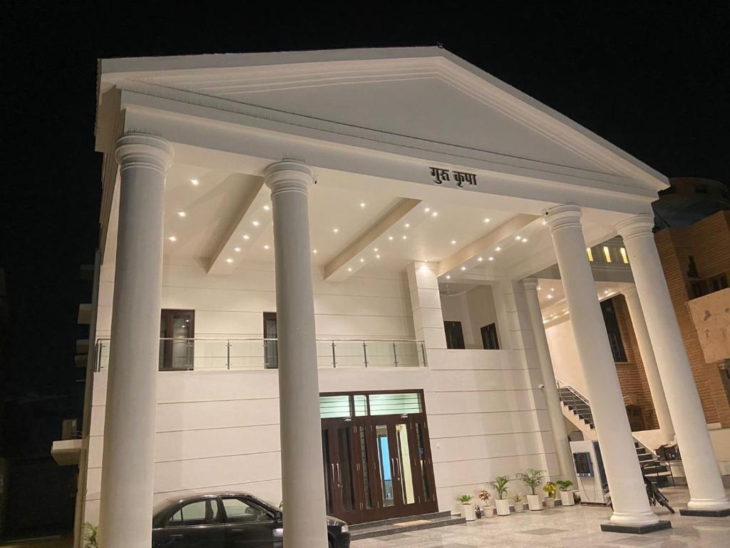 焦特布尔Guru Kripa House的前面有柱子和汽车的大型白色建筑