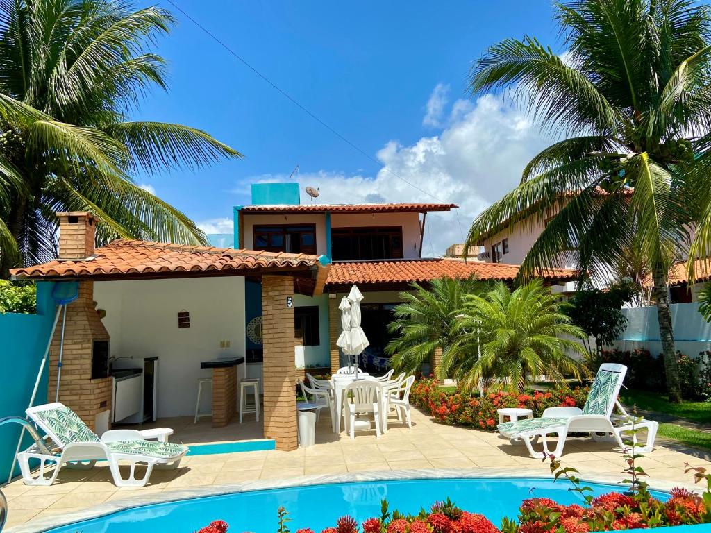 帕里普埃拉Casa de praia aconchegante em Sonho Verde的一座别墅,设有游泳池和棕榈树