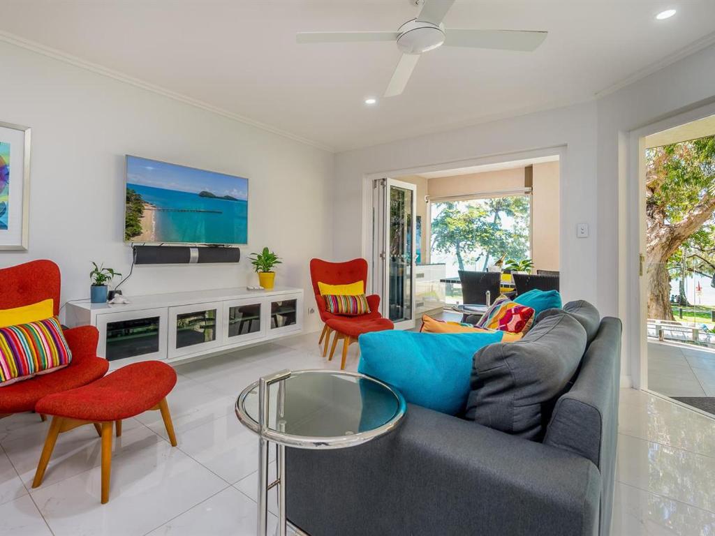 棕榈湾Coral Horizons by Elysium Collection的客厅配有灰色的沙发和红色的椅子