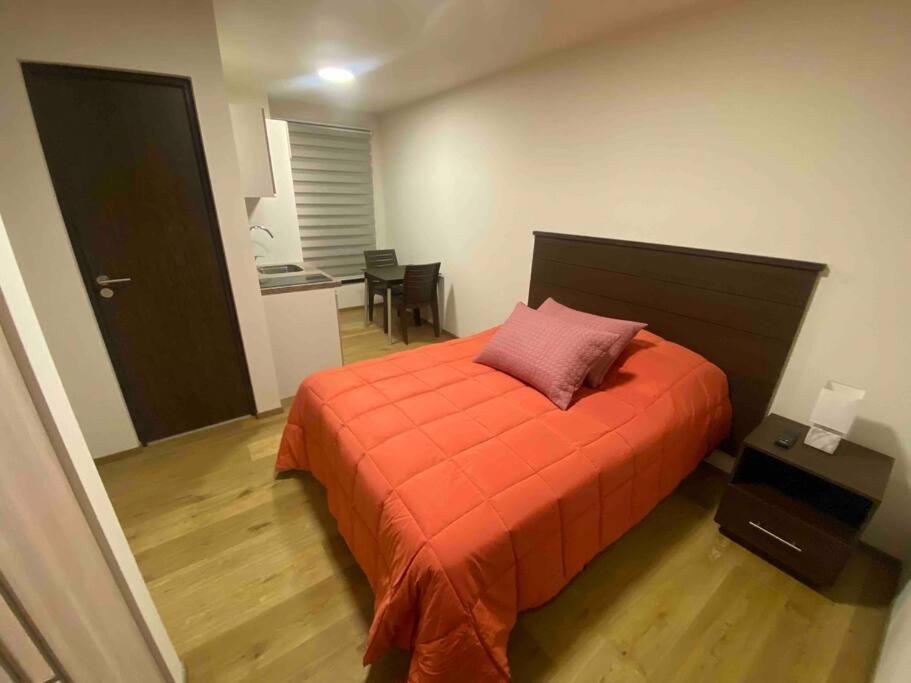 科恰班巴Smart studio的一间卧室配有一张带橙色棉被的床