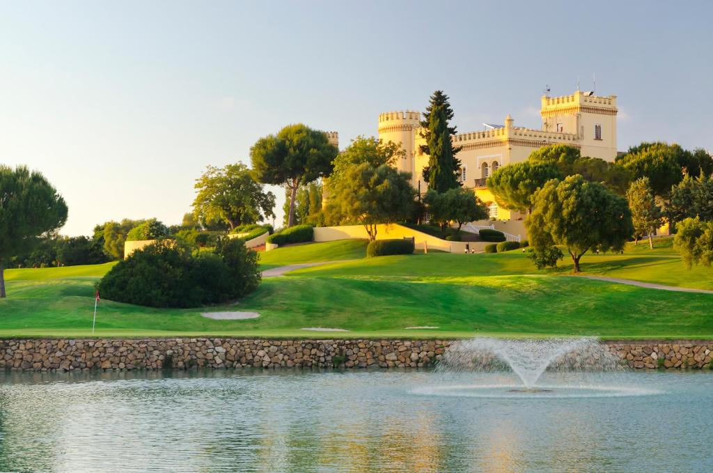赫雷斯-德拉弗龙特拉巴瑟罗蒙蒂卡斯提罗高尔夫酒店的一座带池塘和大楼的高尔夫球场