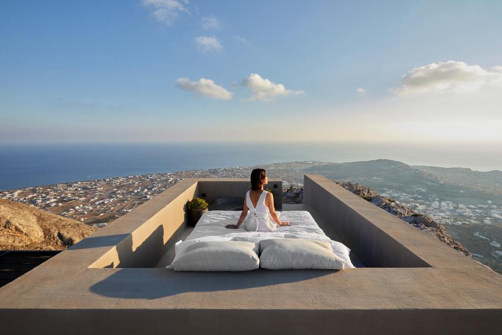 皮尔戈斯Santorini Sky, The Lodge的坐在山顶上床边的女人