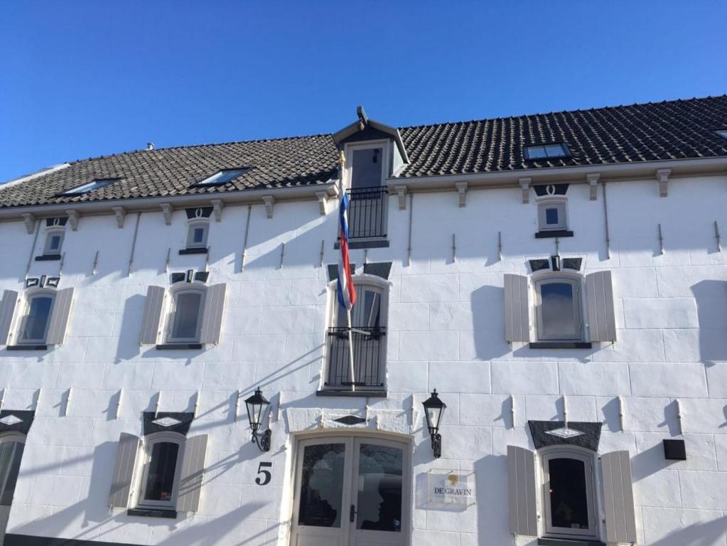斯赫拉芬赞德格拉维酒店的一座白色的大建筑,上面有旗帜
