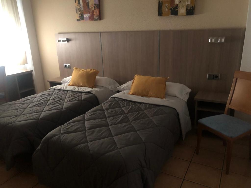 瓦尔德莫罗Hostal De La Rosa的酒店客房,配有两张床和椅子