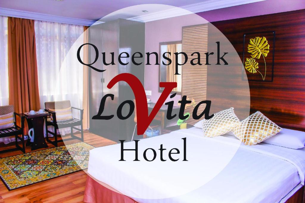 马六甲Queenspark Lovita Hotel的酒店客房,设有床铺和酒店标志