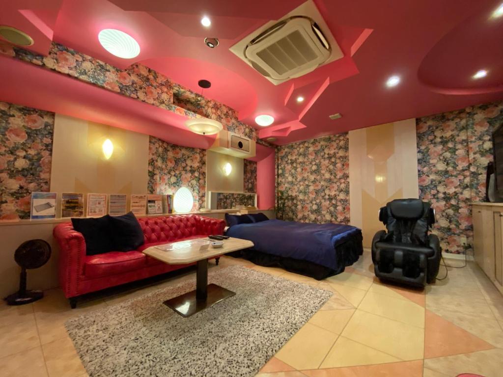 Settsu沙邦酒店（仅限成人入住）的客厅配有红色的沙发和桌子