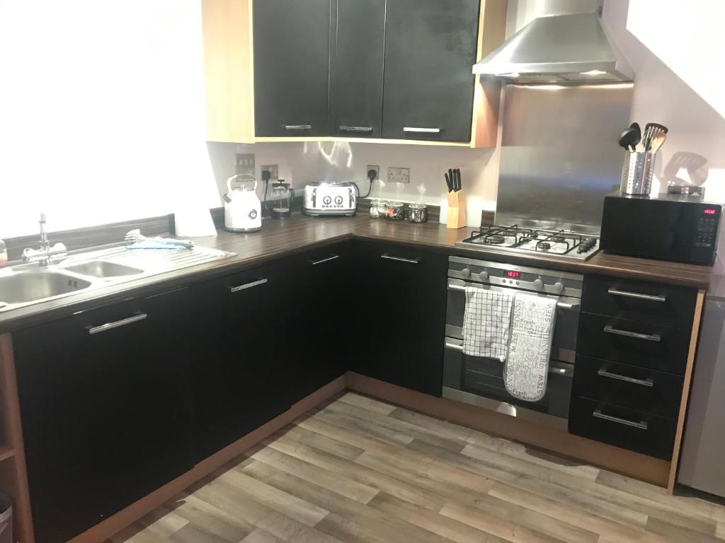 牛顿阿伯特Stunning 2-Bed Apartment in Newton Abbot的厨房配有黑色橱柜、炉灶和水槽。