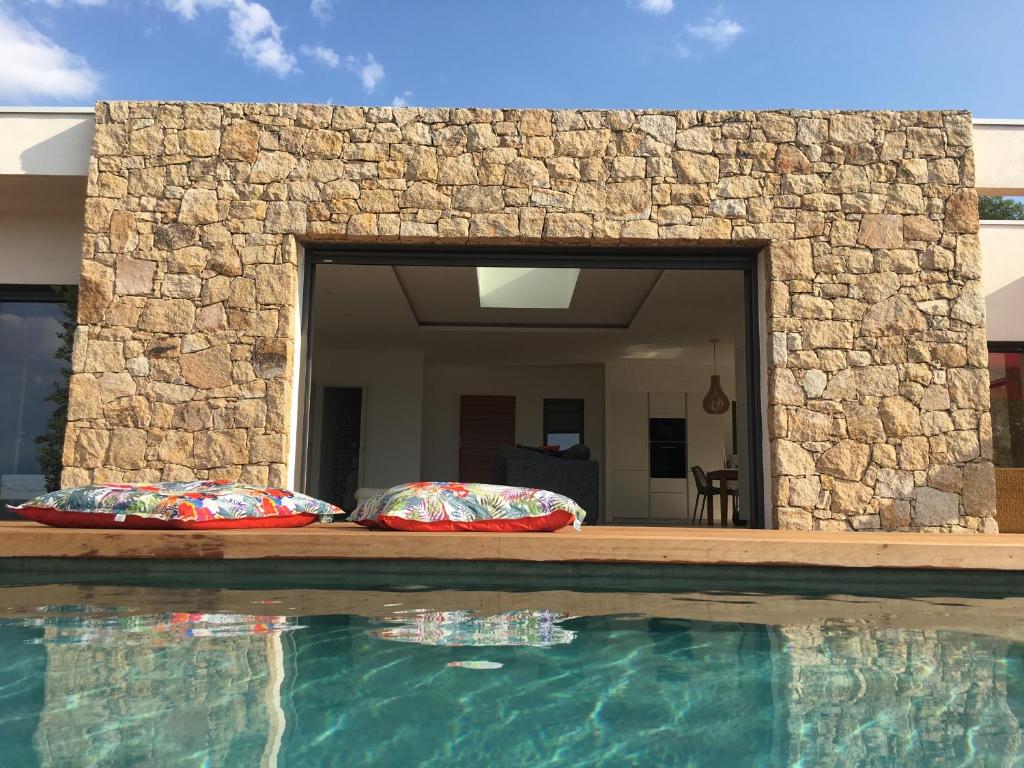 皮耶特罗塞拉Villa Alandra的一座带两个枕头的游泳池,毗邻石墙