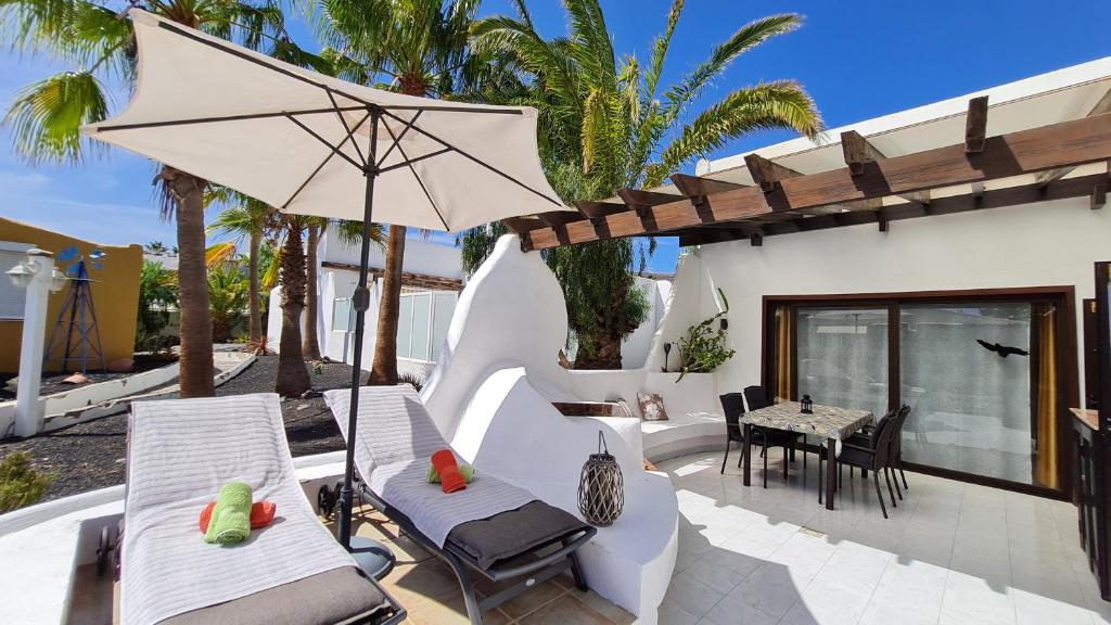 莫罗德哈布雷Casa EL JARDIN的庭院配有椅子、遮阳伞和桌子。