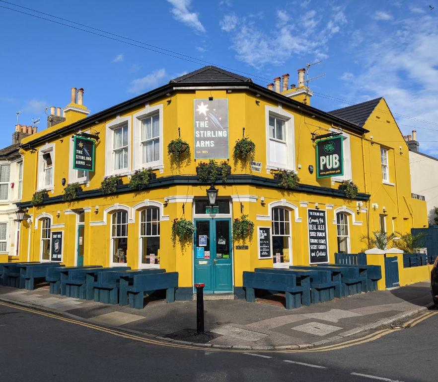 布莱顿霍夫The Stirling Arms Pub & Rooms的前面有蓝色长椅的黄色建筑