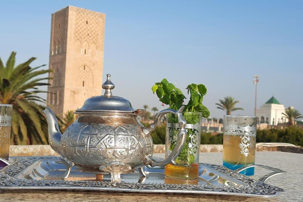 拉巴特Hassan Tower and The Marina come to you的一张桌子,上面放着茶壶和两杯啤酒