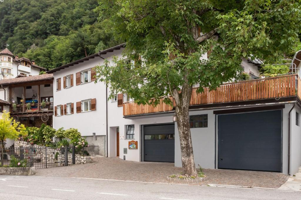 萨洛尔诺Agritur E-Cinque的白色的建筑,有两个车库门和一棵树