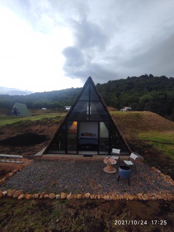 瓜塔维塔Refugio El Cacique的一座黑色三角形房子,在田野里设有壁炉