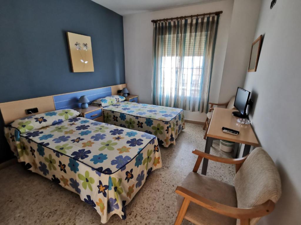 Talavera la Real塔拉韦拉旅馆的一间卧室配有两张床、一张桌子和一张桌子