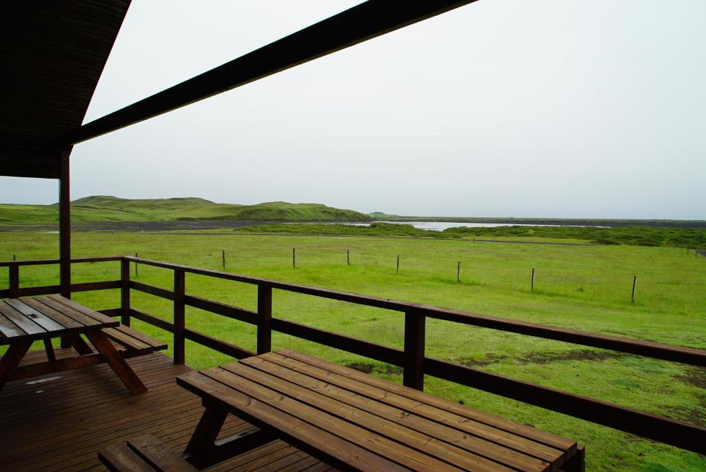 教堂城Riverside Lodge with breathtaking view的木甲板设有长凳,享有田野美景