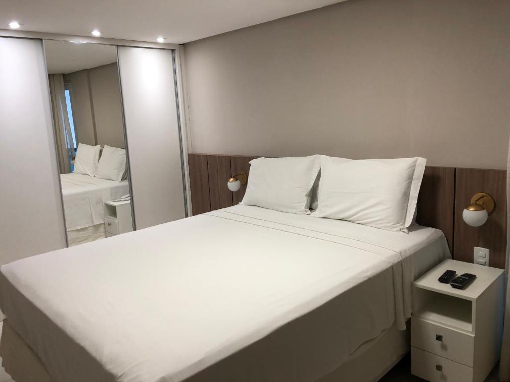 若昂佩索阿Flat Beira Mar de Tambaú apto 206的卧室配有一张白色大床和镜子