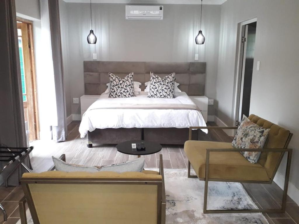 海姆维尔Sani Pass Manor Guest House的一间卧室配有一张床、一张沙发和一把椅子