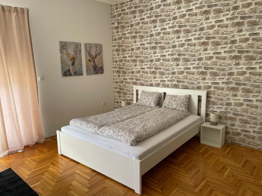 松博尔Apartman Sunny的卧室配有白色的床和砖墙