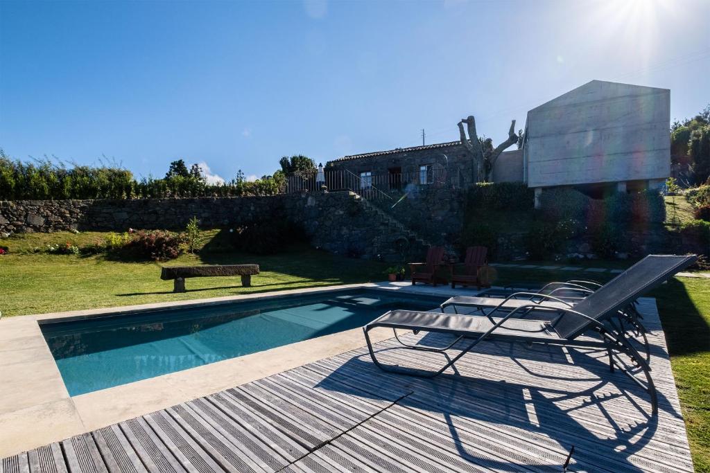 诺德什蒂Casa do Castanheiro - Nordeste, Açores的一个带两把椅子的游泳池,甲板上设有长凳