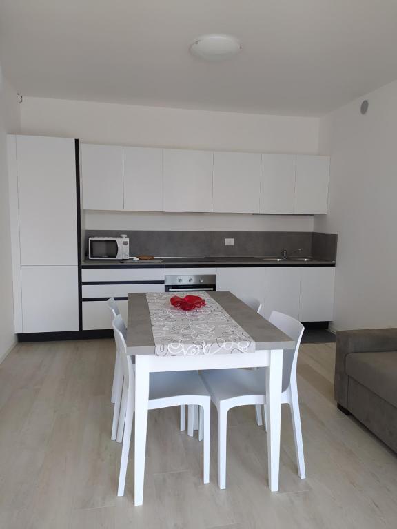 利多迪耶索罗Jesolo Appartamenti F2 - Coral Red的白色的厨房配有白色的桌子和椅子