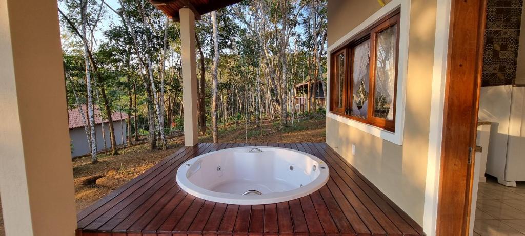 伊塔卡雷Chalés Pura Vida的浴缸位于木甲板上,设有窗户