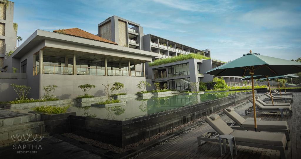 苏丹巴特利Saptha Resort and Spa的一座带游泳池和遮阳伞的建筑